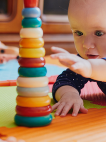 Baby liegt auf dem Bauch und greift nach Spielzeug