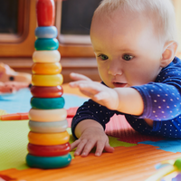 Baby liegt auf dem Bauch und greift nach Spielzeug