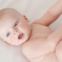 baby liegt auf dem Rücken und fasst nach seinen Füßen