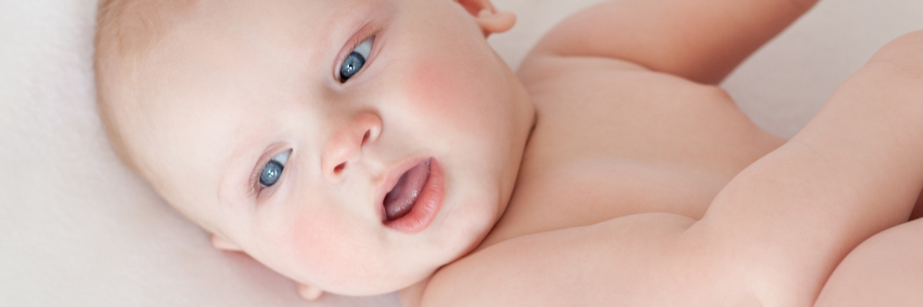 baby liegt auf dem Rücken und fasst nach seinen Füßen