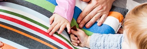 mehrere Kinder und Erwachsenenhände auf einem Kissen