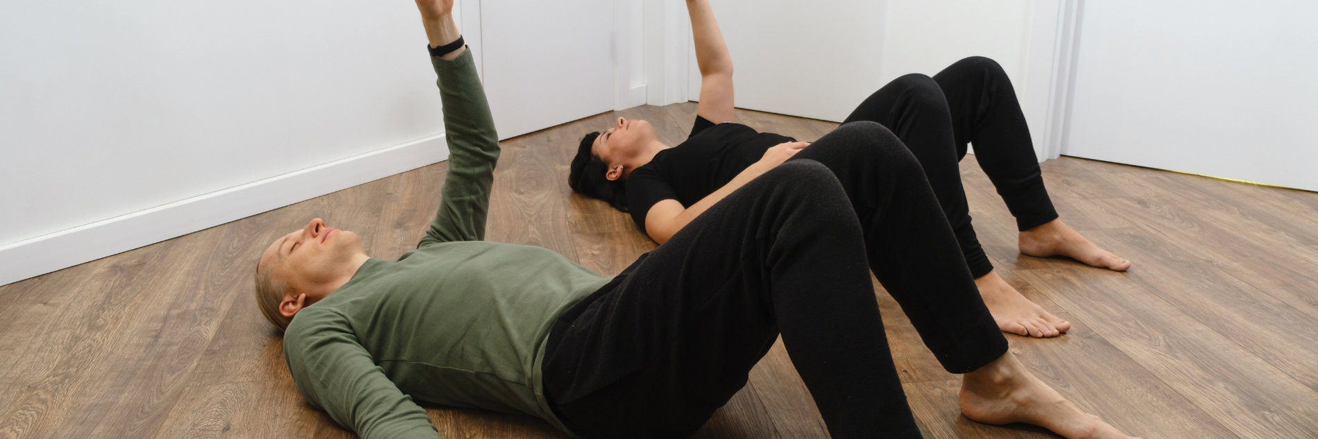 zwei Menschen auf dem Rücken liegend mit gymnastischen Bewegungen